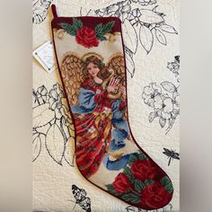 a christmas stocking with an angel and roses on it is hanging on a wall