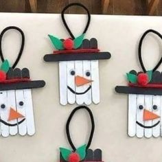 four popsicle snowmen are hanging on the wall