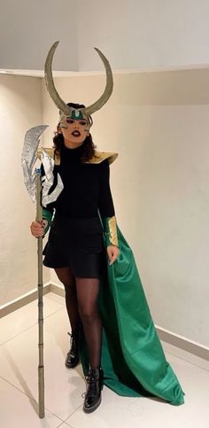 a woman dressed as loki with horns on her head and green cape holding a staff