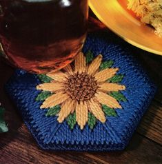 there is a blue coaster with a yellow flower on it next to a glass of tea