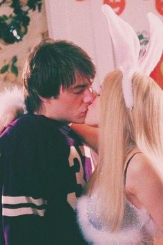 a man and woman kissing in front of a christmas tree