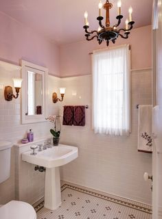 a bathroom with a chandelier, toilet, sink and window in the corner