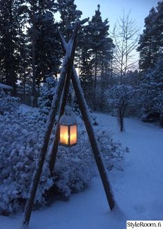 a lantern is lit in the middle of a snowy forest