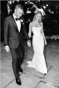 a bride and groom are walking down the street holding hands in black and white photo