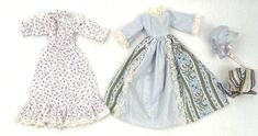 two dolls dressed in blue and white dresses, one is wearing a dress with flowers on it