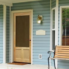 a wooden bench sitting in front of a door on a blue house with white trim