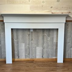 a white fireplace surround with wood paneling on the wall