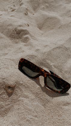 a pair of sunglasses laying in the sand