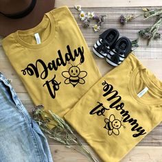 two shirts that say daddy to me and mommy to bee on them, next to some shoes