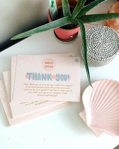 thank you note sitting on top of a desk next to a potted plant and other items