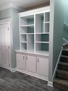 an empty room with white bookcases and stairs