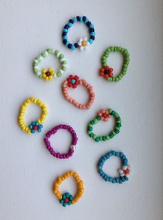 several different colored bracelets are arranged on a white surface, with beads in the shape of rings