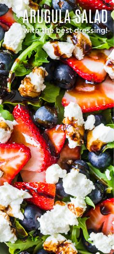 a salad with strawberries, blueberries and feta cheese on top is shown