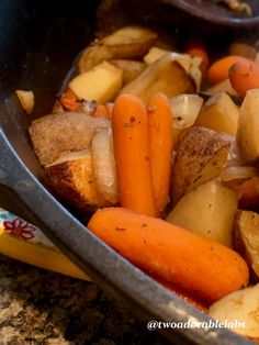 a pan filled with potatoes and carrots on top of a counter