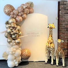 two giraffes are standing in front of a backdrop with balloons and decorations