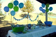 the table is set up with balloons and other items for an outdoor birthday party or baby shower