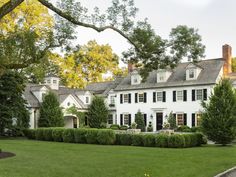 a large white house surrounded by trees and grass