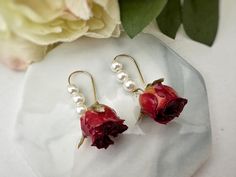 Embrace the beauty of nature with our Real Rose Earrings. This exquisite piece of handmade jewelry features real pink roses carefully preserved in resin, capturing their delicate essence for eternity. The main material, real flowers, symbolizes growth, love, and the fleeting beauty of life. Each pair of earrings is meticulously crafted to showcase the unique charm of these natural blooms, making it a perfect gift for birthdays or special occasions. Wear these Real Rose Earrings with pride and le Delicate Rose Earrings For Gift, Delicate Rose Design Flower Earrings For Gift, Elegant Rose Dangle Earrings, Elegant Rose Earrings With Ear Wire, Jewelry Pearl Earrings, Real Flower Earrings, Real Rose, Jewelry Pearl, Botanical Jewelry