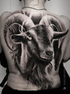 a woman's back with a goat tattoo on it