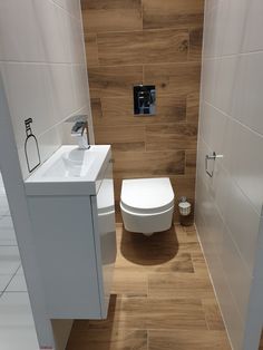 a white toilet sitting in a bathroom next to a sink and wooden flooring on the walls