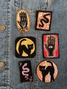 four patches with cats on them sitting in the back pocket of someone's jean jacket