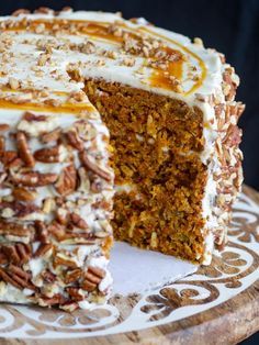 a carrot cake with white frosting and pecans on the top is cut in half