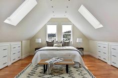 an attic bedroom with white furniture and wooden floors