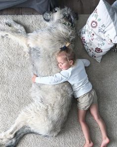 a small child laying on the floor next to a dog