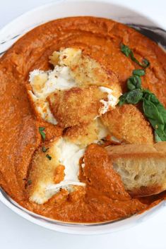 a white bowl filled with red sauce and bread