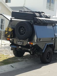 an army vehicle is parked on the side of the road in front of a house