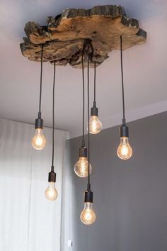 five light bulbs hanging from a wooden beam in a room with grey walls and white curtains