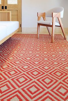 a bedroom with a bed, chair and rug in the middle of it on hardwood flooring