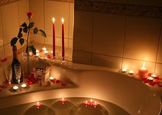 a man is in the bathtub surrounded by candles and roses