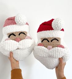 two knitted santa claus mittens are being held by someone's hands, both wearing red and white hats