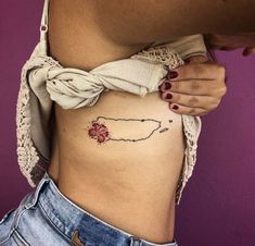 a woman's stomach with a small flower tattoo on the side of her belly