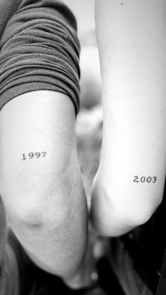 two people's legs with numbers tattooed on them