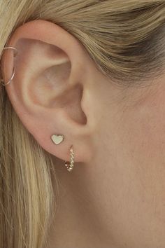 a close up of a woman's ear with two small hearts attached to it