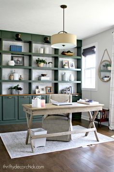 a home office with green bookcases and white rug in front of the desk