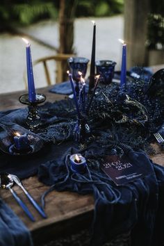 a table topped with blue candles and black cloth