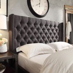 a bed with white sheets and pillows in a bedroom next to a clock on the wall