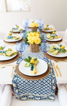 the table is set with yellow flowers and blue napkins, plates and utensils