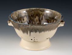 a silver and black bowl on a white base with blue trim around the rim, in front of a gray background