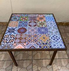 a table with many different colored tiles on it's top and bottom half, sitting on a tile floor