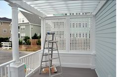 a white pergolan on the side of a house with a ladder and bucket