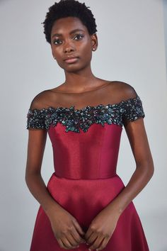 a woman in a red dress with an off the shoulder top and beaded shoulders