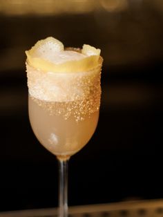 a close up of a drink in a wine glass with ice and lemon wedges