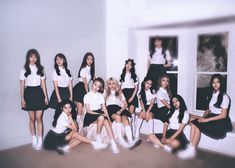 a group of young women sitting next to each other in front of a white wall