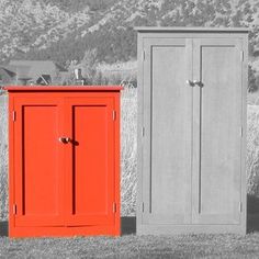 two orange and gray cupboards sitting next to each other on the grass in front of a mountain