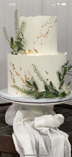 a three layer white cake with greenery on top