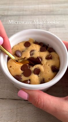 a person holding a spoon in a bowl filled with chocolate chip cookie dough and pudding